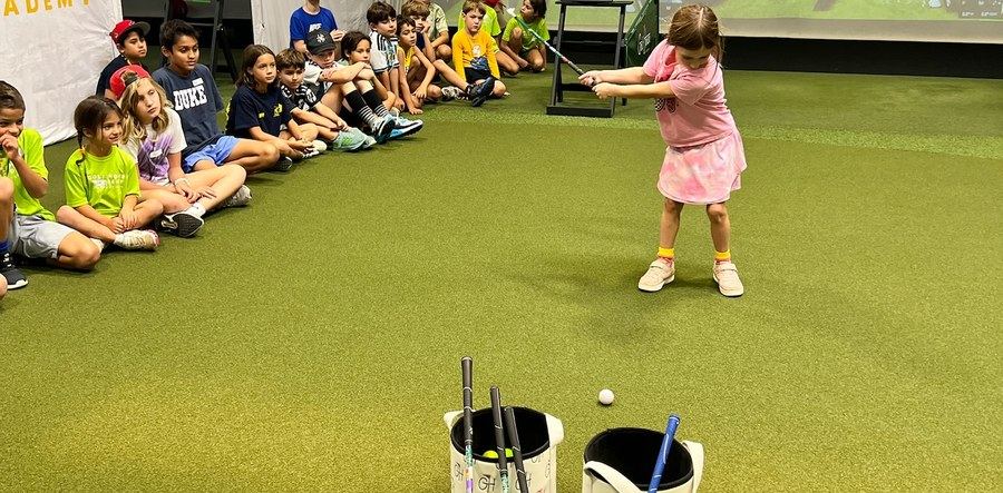 Kids watching a putting challenge at a Golf House Academy camp