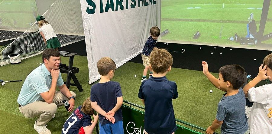 A coach helping kids with their putting at Golf House Academy